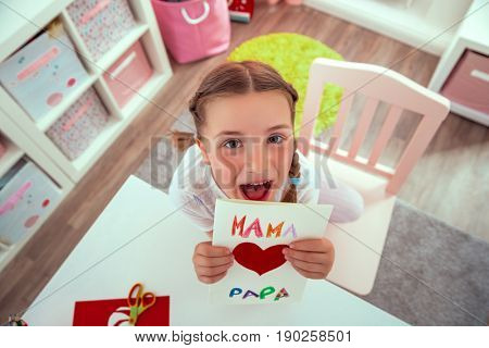 girl surprising parents with greeting card at home