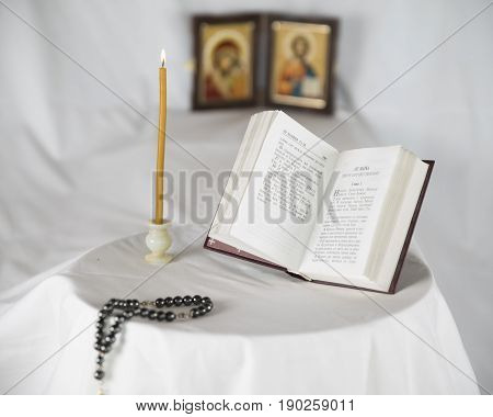 Candle, rosary and gospel and orthodox icons.