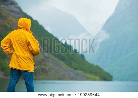 Tourism vacation and travel. Male tourist looking at mountains and fjord Sognefjord in Norway Scandinavia. Misty foggy day rainy weather