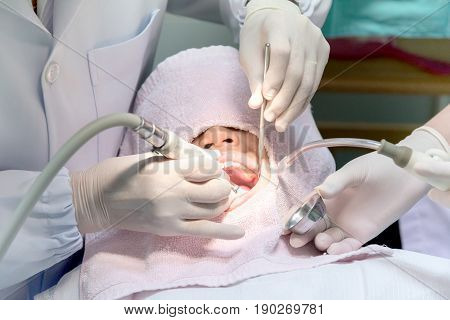 Close up of young Asian Pre teen girl having dental professional treatment in stomatology clinic. Kid at dental office dentist examining and cleaning her teeth of tartar and plaque.