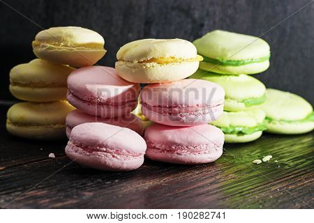Assorted colorful macaroons. Sweet macarons with fresh berries on dark background with copy space.