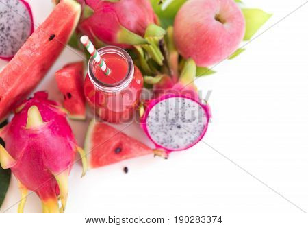 Tropic flat lay top view tropical summer concept with pink tropical watermelon apple dragon fruits and smoothie juice palm leaves and plumeria on white