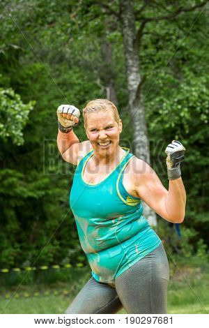 Stockholm Sweden - June 03 2017: Close up front view one caucasian chubby woman. Wet happy and smiling after completing a mud obstacle at the annual event Toughest Stockholm.