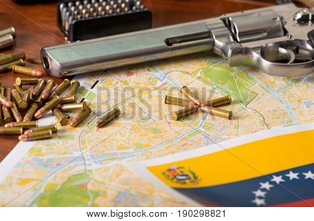Close up of a shotgun and a revolver, cartridge belt with bullets with a blurred Venezuelan flag, on wooden table.