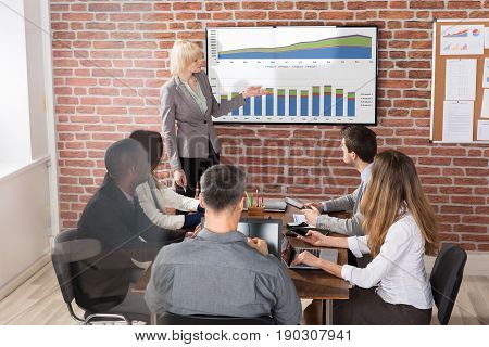 Young Blonde Businesswoman Giving Presentation To Her Colleague In Office