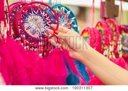 OTAVALO, ECUADOR - MAY 17, 2017: Close up of a woman holding a pink catchdreamer in her hand, in colorful market background.