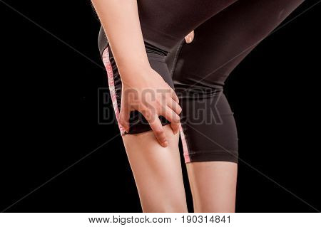Running sport injury woman athlete joggermassaging calf muscle before workout in black background.