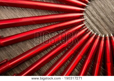 A Lot Of Red Pens In A Circle On A Black Wooden Background. Concept Office Or School, Knowledge Day,