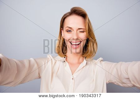Selfie Time! Close Up Of Attarctive Young Blond Lady In A Beige Shirt, Standing On The Pure Backgrou