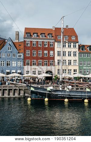 Copenhagen Denmark - August 11 2016: Nyhavn a cloudy day. It´s a 17th-century waterfront canal and entertainment district in Copenhagen lined by coloured townhouses it has many historical wooden ships.
