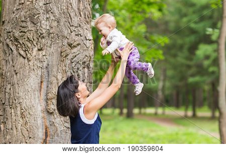 happy family - Mother throws up baby, playing outdoors.