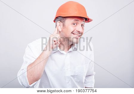 Portrait Of Contractor Wearing Hardhat Making Can't Hear Gesture