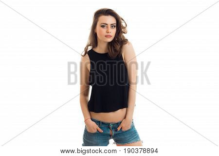 beautiful young brunette posing in the Studio and keeps his hands in his pockets is isolated on a white background