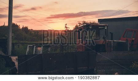 An abandoned place with equipment on the background of sunset.