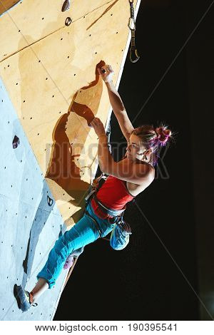 woman climber climbs with rope on climbing gym. woman mekes hard wide move. Climbing competition