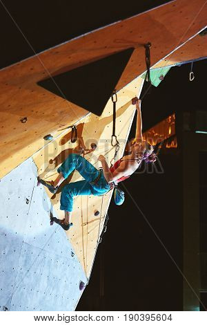 woman climber climbs with rope on climbing gym. woman mekes hard wide move. Climbing competition