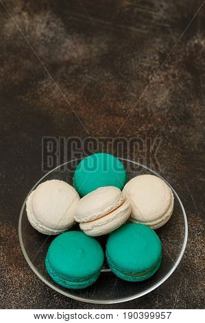 Cake macaron or macaroon on brown background teal and white almond cookies on plate copyspace