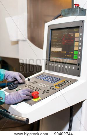 Worker hands on the control panel of a computer numerical control programmable machine. Milling and lathe industry. CNC technology. Metal engineering.