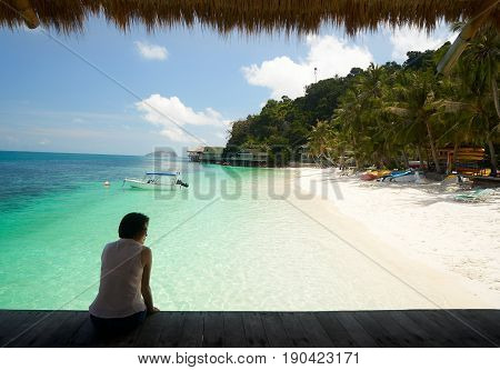 Silhouette women sit on wooden jetty with rooftop beside tropical sea in sunny day Rawa island . Malaysia .
