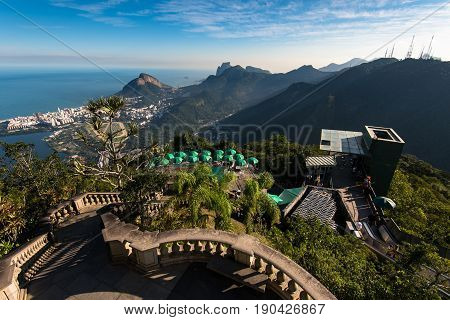 Rio de Janeiro, Brazil - May 24, 2017: View of Tijuca forest mountains from the Corcovado Mountain, with green umbrellas below, and a staircase to Christ the Redeemer statue.