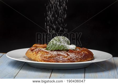 tarte tatin with icing suger on white wood
