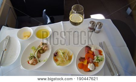FRANKFURT, GERMANY - SEPTEMBER 28, 2014: First Class Dining onboard an Boeing 747 upper deck from Lufthansa, white wine, water and appetizer.