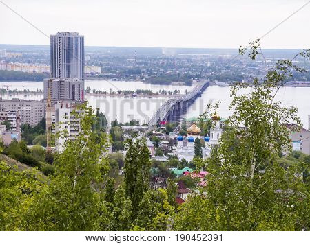 Road bridge between the cities of Saratov and Engels. Urban landscape, architecture. Multi-storey building. Blooming lilac bushes in the foreground.