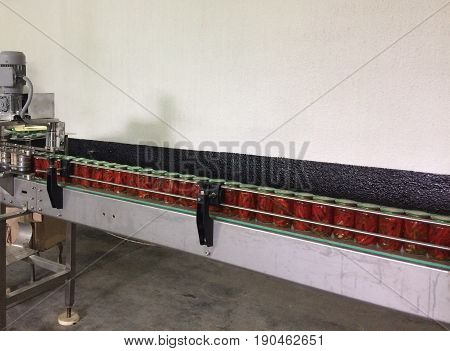 Working process of the production of Preserved red hot chili peppers on cannery. Pasteurization of cans. Movement on the conveyor.