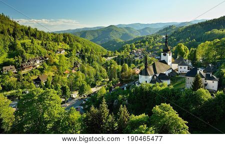 Spring in Slovakia. Old mining village. Historic church in Spania dolina. Springtime colored trees at sunset.