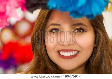 Close up of a smiling woman hiding behind a magenta catchdreamer, in colorful market background