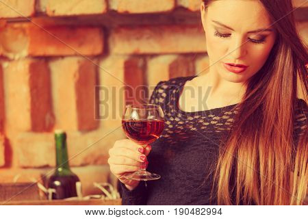Elegant beauty lady long hair full make up wearing black dress tasting wine in rural cottage interior celler