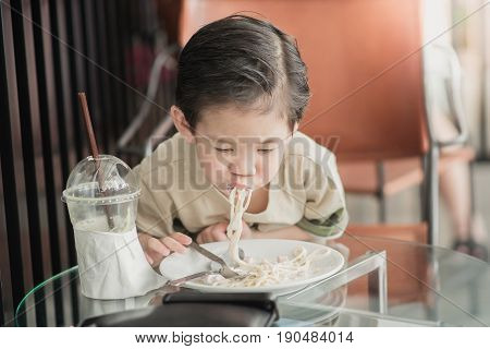 Cute Asian chid eating Spaghetti Carbonara in restaurantvintage fiter
