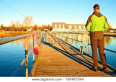 Tourist Wlk On Wharf Construction Above  Sea To Harbor. Clear Blue Sky, Calm Water Level