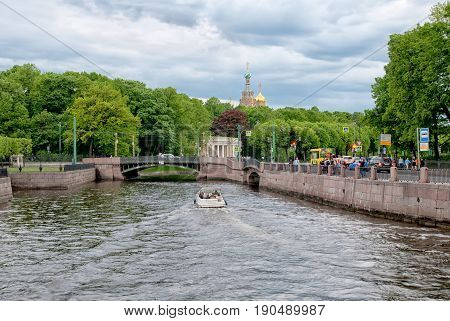 SAINT - PETERSBURG, RUSSIA - JUNE 8, 2017: White boat with tourists sails along  the embankment of The Moika River near Mikhailovsky Garden in summer white night