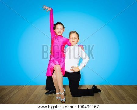 The young boy and girl posing at dance studio on blue. The ballroom dancing concept