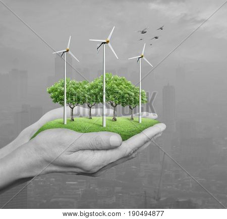 Wind turbines grass and trees in human hands over pollution city Ecological concept