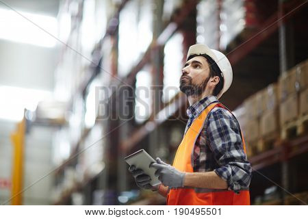 Worker with touchpad revising goods in storehouse
