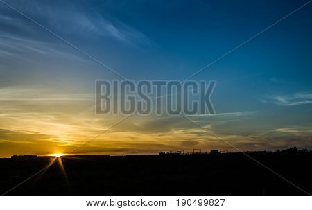 Sun setting over cow pasture on summer night