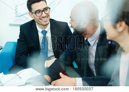 Happy businessman listening to co-worker during conversation