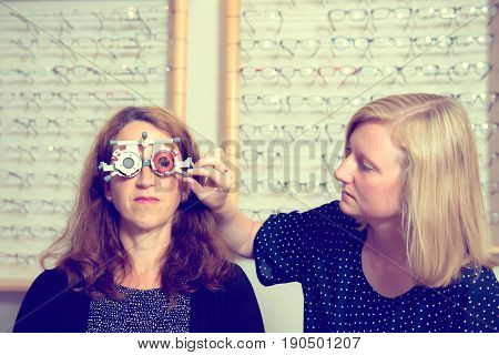 Female Optican Checking Eyes Of Woman For New Glasses