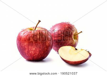 Two red apples (Malus domestica Malus pumila or Pyrus malus) with drops of water and a quarter of fresh apple with seeds isolated on white background