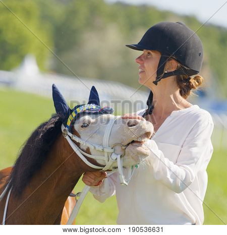 STOCKHOLM SWEDEN - JUNE 06 2017: Woman strokes a cute pony gallop race horses on the muffle at Nationaldags Galoppen at Gardet. June 6 2017 in Stockholm Sweden