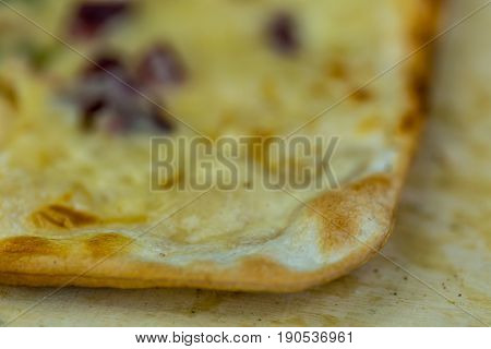 Macro shot of a pizza tarte flambee with details on the crusty foreground and blurry background