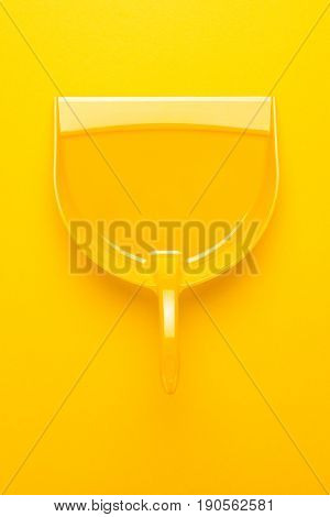 top view of plastic dustpan. dustpan on yellow background. bright yellow dustpan. plastic dustpan vertical shot