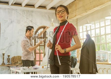 Young asian female desiner standing with desiner team working in the studio.