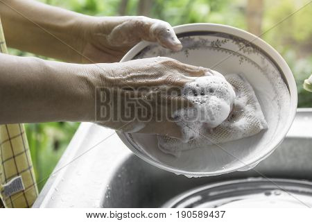 Close up hands of woman washing dishes in the kitchen.