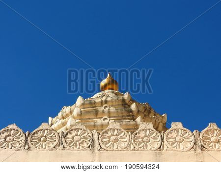 The golden shikhar of a temple's dome in Saputara, India, shines vibrantly against the brilliant blue of the clear sky