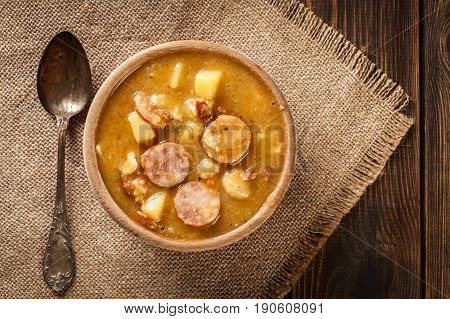 Wooden Bowl Of Split Pea Soup With Sausage And Potatoes