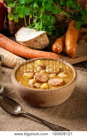 Wooden Bowl Of Split Pea Soup With Sausage And Potatoes