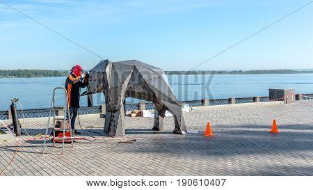 Samara, Russia - June 2017 - Welder on the street makes an elephant of the iron city concept on the embankment of the river Volga, Samara.